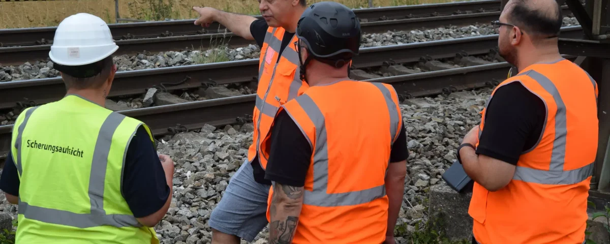 SDL-Team beim Ortstermin an einer Bahnstrecke mit fester Absperrung