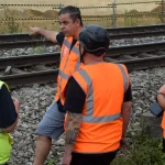 SDL-Team beim Ortstermin an einer Bahnstrecke mit fester Absperrung